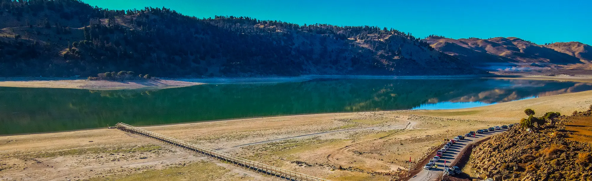 Le lac Sidi Ali et ses rives, entouré des montagnes boisées du Moyen Atlas